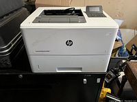 Frontal view of the HP LaserJet Enterprise M506 printer showing the front paper tray and HP logo.
