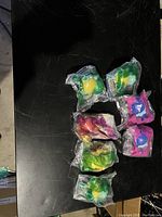 Seven individually sealed Pokémon collectible toys from McDonald's promotional set arranged on black surface. Included characters: Squirtle (3), Popplio (2), Psyduck (1), Eevee (1).