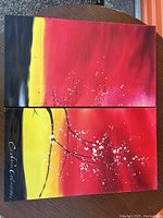 Full view of two signed abstract canvas paintings displayed together, showing vibrant colors and signatures