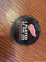 Top side of the puck showing 'I Played At The Joe' text and Detroit Red Wings logo.