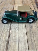 Side view showing green body with tan convertible top, number 3 on door, red interior, and detailed wheels