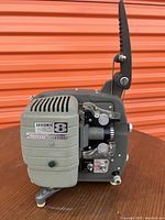 Side view of vintage Sekonic 8 Autoload film projector showing lens assembly, controls, ventilation grille and film reel arm.