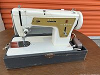 White and gold Singer Model 337 sewing machine, showing the machine on a flat surface with visible spool pins, needle area, and front control levers.