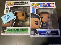 Photo showing boxed Jean-Michel Basquiat and Dom POP! vinyl figures from the front, with clear view of packaging and figure details.