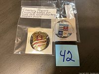 Two Soviet badges in protective sleeves, one with red shield and hammer and sickle, the other with blue and white design showing ships and text