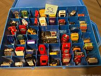 Blue plastic storage case with approximately 41 diecast toy cars inside, showing various models and colors, neatly organized in compartments.