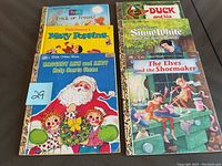 Photo showing nine Little Golden Books arranged in two rows with colorful illustrated covers featuring Winnie the Pooh, Mary Poppins, Raggedy Ann and Andy, Snow White, and others.