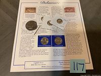 Photo of Delaware themed coin card with three plastic enclosed coins graded UNC from 1967, 1974, and 1969, with two vintage postage stamps attached to card