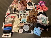 Photo showing all hair accessories laid out on floor including various scrunchies, claw clips, coil hair ties, bobby pins, and hair bands.