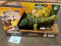 Side view of Nigersaurus toy in original box showing partial wear and tear on packaging