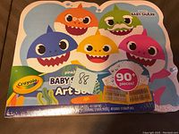 Top view of the Crayola Baby Shark Art Set packaging showing Baby Shark characters and key features including quantity of items and contents such as crayons and sticker sheets.