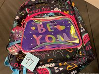 Clear view of the black backpack with colorful positive graphics and a transparent front pocket reading 'BE YOU' in rainbow letters.