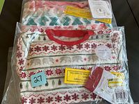 Two sealed packages of new children's pajamas, one red collar with holiday pattern, one floral pattern.