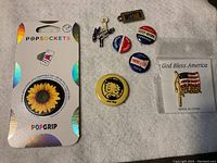 Photo of PopSockets PopGrip with sunflower design and seven assorted pins including patriotic and vintage styles.