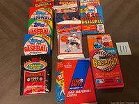 Overhead view of multiple unopened sports trading card packs and boxes arranged on floor including baseball, football, and hockey cards from years 1987 to 1992.