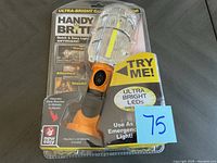 Front view of the cordless work light in clear plastic packaging showing product details and labels.