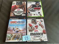 Four used PlayStation 2 sports games arranged in a 2x2 grid: Tiger Woods PGA Tour 2004, NFL 2K3, Summer Athletics The Ultimate Challenge, Madden NFL 2004. Each game in original cases with cover art visible.