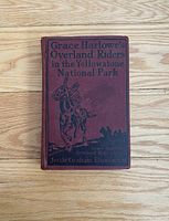 Front cover of the antique book 'Grace Harlowe's Overland Riders in the Yellowstone National Park' showing maroon cloth with black text and illustration.