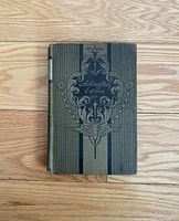 Front cover of the antique book "Arlington Edition" with decorative design in black and gold on a greenish fabric cover.