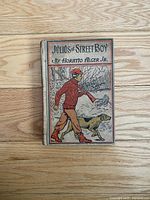 Photo of the front cover of the antique book featuring a boy and dog illustration.