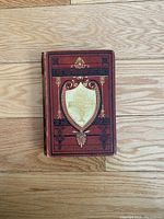 Photo of the antique closed book showing the detailed embossed cover with gold and black design.