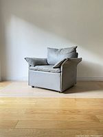 Side profile view of gray leather armchair on wood floor