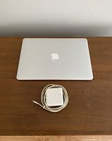 Closed laptop with coiled MagSafe 2 charger on wooden surface