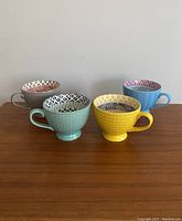 All four mugs displayed side by side showing exterior colors and interior designs.