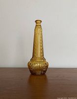 Clear front view of the amber glass genie bottle showing detailed embossed pattern and narrow neck.