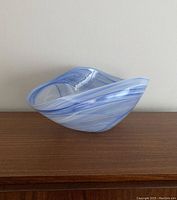 Front view of blue swirled vintage glass bowl on wooden surface against light wall.