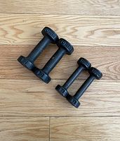 Four vintage York dumbbells arranged in pairs by weight on wooden floor, 2 lb and 1 lb pairs