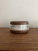 Front view of vintage kitchen scale showing brown top and base with silver dial in between, displaying pounds and kilograms measurement