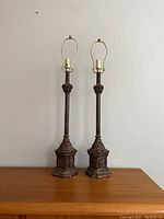 Pair of tall vintage table lamps against a plain wall on wooden surface