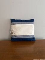 Front view of square pillow with blue top and bottom borders and white center area with stripes.