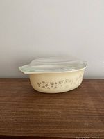 Side view of the vintage Pyrex casserole dish with lid showing beige exterior and floral pattern.