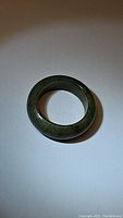 Top view of natural untreated green Myanmar jade ring on white background, showing smooth polished surface and rounded shape.