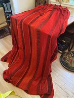 Full view of both cherry red pleated drapery panels draped over table
