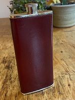 Full view of burgundy leather-wrapped flask standing upright