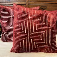 Two matching cranberry cut-velvet pillows on sofa