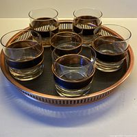 Tray holding six lowball glasses showing copper sleeves and tray rim.
