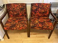 Pair of matching wooden frame armchairs with orange-red abstract fabric upholstery