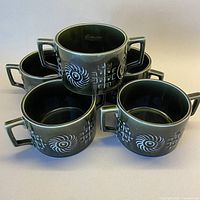 five dark green handled soup bowls stacked