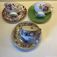 Three teacup and saucer sets displayed