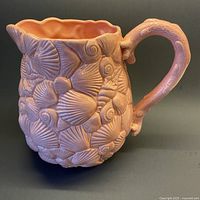 Full view of pitcher showing seashell relief and handle
