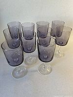 Front angled view of all 10 violet wine glasses showing shape and color