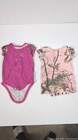 Two baby girls short sleeve pajamas onesies side by side against white background.