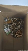 Costume jewelry pieces including faux pearl necklaces, rhinestone bracelet, a gold-tone sunburst brooch, and other assorted pieces in a box.