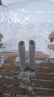 Photo showing two white ribbed flower pots standing on a wooden deck with snow in the background
