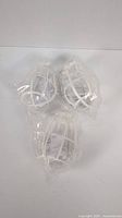 Three white plastic light bulb cage protectors in clear plastic packaging.