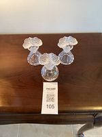 Three crystal perfume bottles with frosted flower stoppers displayed on a wooden surface.